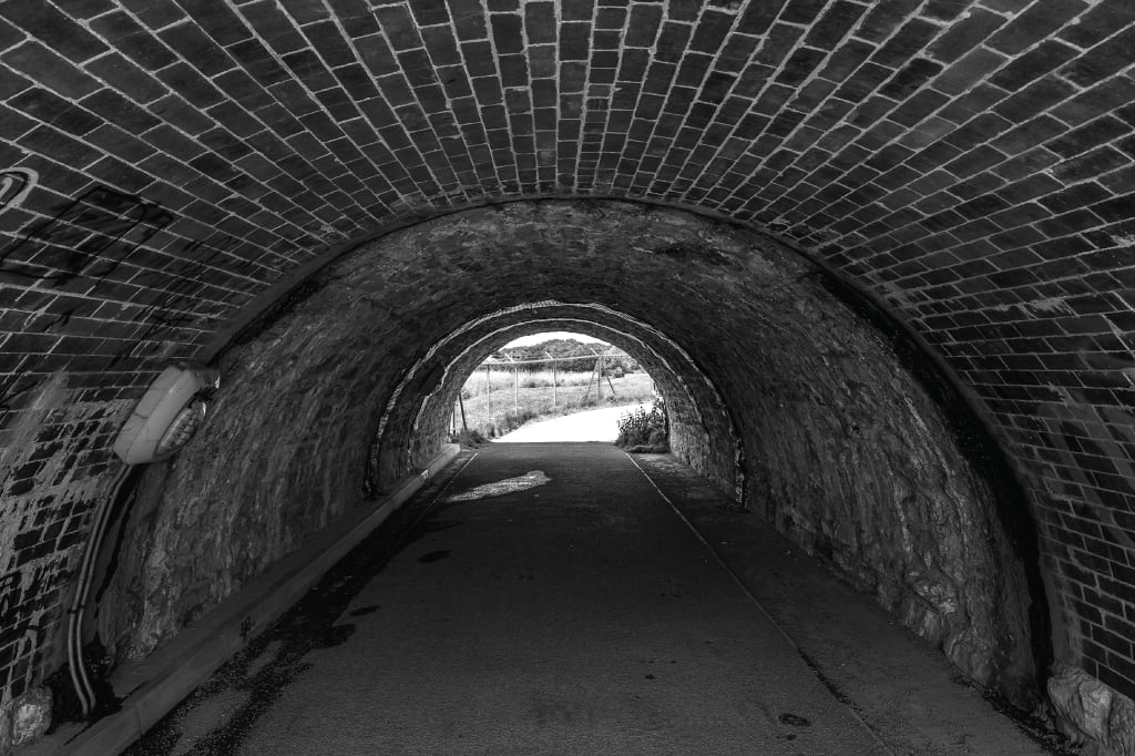 Showing an old brick railway tunnel in Newton Abbot, Devon, with graffiti. The tunnel was built by Isambard Kingdom Brunel for his broad gauge railway